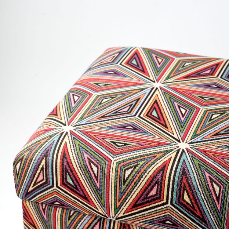 Un pouf coloré avec un motif floral et un espace de rangement, rembourré, sur des pieds foncés