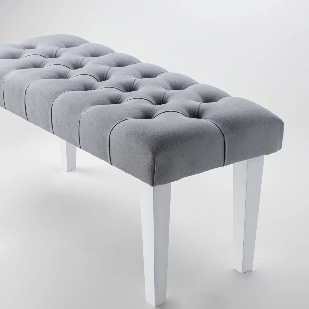 Banc élégant en gris avec revêtement matelassé et pieds blancs