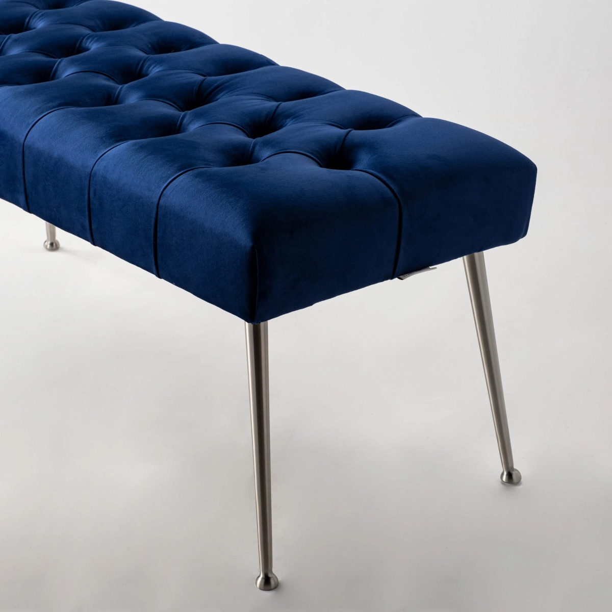 Banc matelassé bleu marine avec pieds en métal, parfait pour les intérieurs de style loft