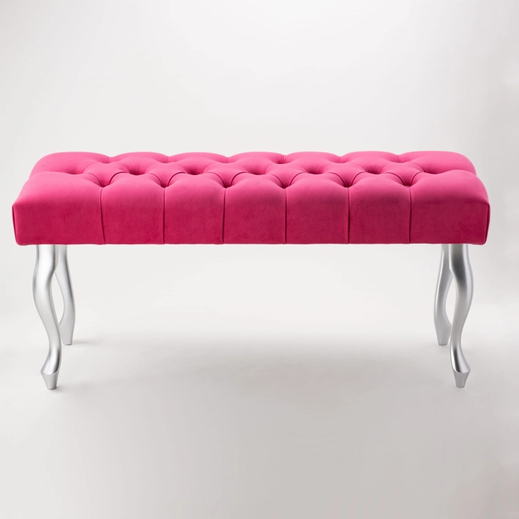 Un banc élégant et matelassé de couleur fuchsia intense avec des pieds argentés.