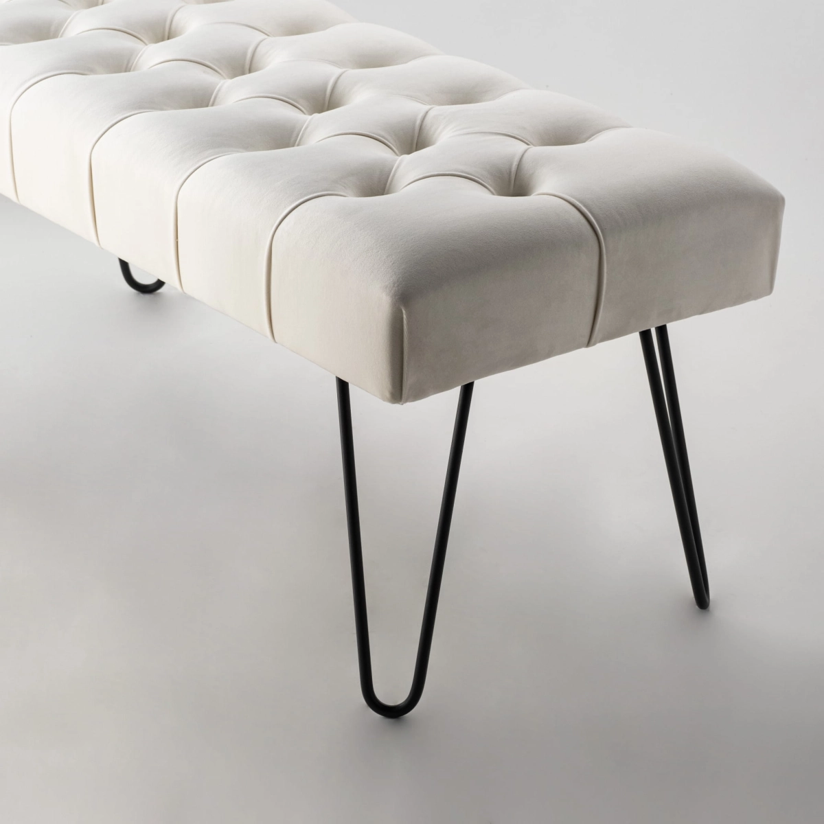 Banc matelassé de couleur crème avec pieds en épingle