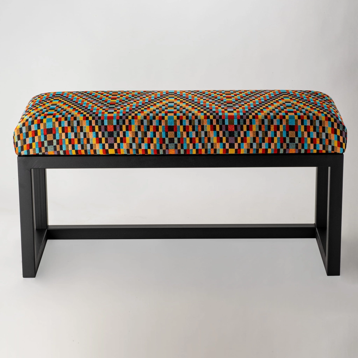 Un banc rembourré à motifs sur pieds en métal, parfait pour les intérieurs loft.