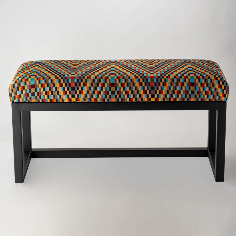 Un banc rembourré à motifs sur pieds en métal, parfait pour les intérieurs loft.